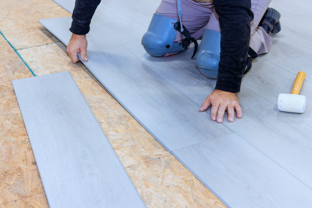 During installation vinyl laminate at floor of new home a worker works